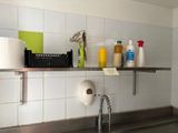 a sink in a kitchen with a lot of cleaning supplies on the shelf