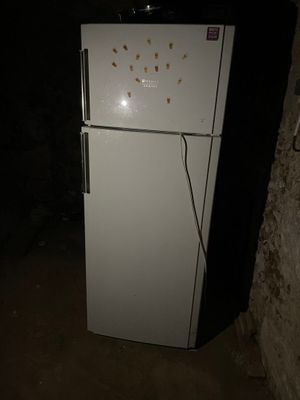 un réfrigérateur blanc sur lequel est posée une horloge, dans une pièce sombre