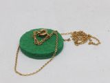 necklace with a gold chain and a green felt disc on a white surface