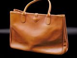 a close up of a brown handbag on a black background