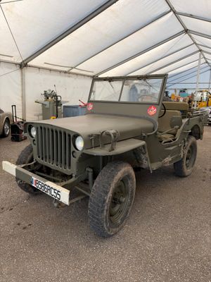 une jeep militaire garée dans une tente, avec d'autres véhicules en arrière-plan