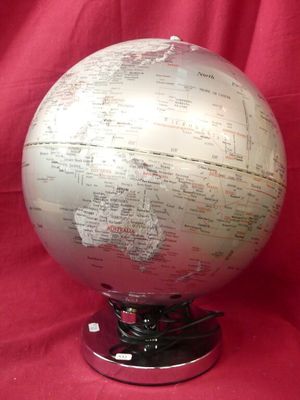 a silver and white globe on a stand on a red cloth
