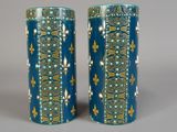 une paire de vases bleus ornés de motifs dorés sur un fond gris