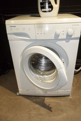 a white washing machine with a bottle of deter on top of it