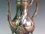 a silver tea pot sitting on a stand on a table