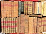 many old books stacked on top of each other in a box