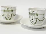 two cups and saucers with designs on them on a white surface