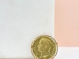 a gold coin sitting on top of a white surface next to a pink and white wall
