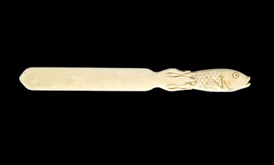 carved wooden spoon with a fish on it on a black background