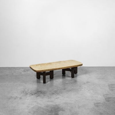 un banc en bois posé sur un sol en béton, près d'un mur blanc