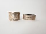 two silver rings with engraved names on them sitting next to each other