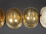 three gold hard hats and a hard hat on a black background