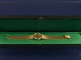 a gold plated watch in a black box on a green surface
