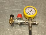 a yellow pressure gauge sitting on top of a metal table