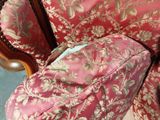 a cat sitting on a chair with a pink cover on it