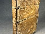 an old book is sitting on a table with a gray background