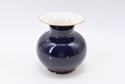 a blue vase with a gold rim sitting on a white surface