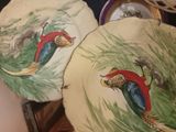 two plates with birds painted on them sitting on a table