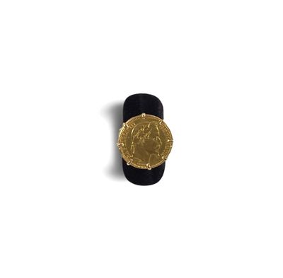 une pièce d'or sur un anneau noir posé sur une surface blanche