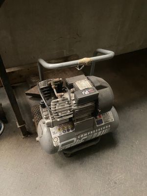 un petit compresseur d'air posé par terre dans un garage