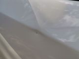 a white car that has a broken door handle on the side of the road