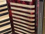 an image of a red accordion sitting on top of a table next to a stack of books