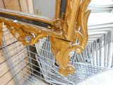 a gold mirror hanging on the wall next to a wire basket