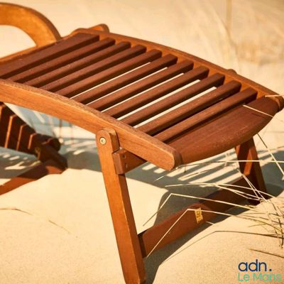 une chaise en bois posée sur le sable de la plage