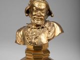 un buste en bronze représentant un homme coiffé d'un chapeau, posé sur un socle