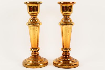two golden candlesticks sitting on a white surface