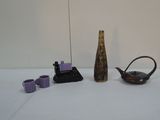 un vase, une théière, une autre théière et des tasses posées sur une table