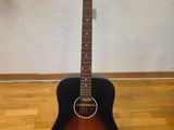 an acoustic guitar sitting on a hard wood floor next to a wall