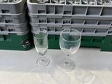 two empty wine glasses sitting on a table next to a rack of empty wine glasses