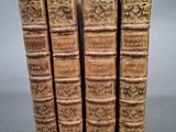 quatre vieux livres sont empilés les uns sur les autres sur une surface grise