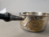 a silver saucepan with a black handle on a table