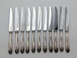 six silverplated knives are lined up on top of each other