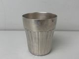 une tasse en métal argenté posée sur une table blanche, sur fond blanc