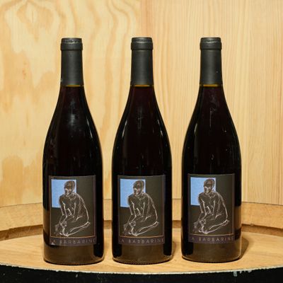 three bottles of wine sitting on top of a barrel