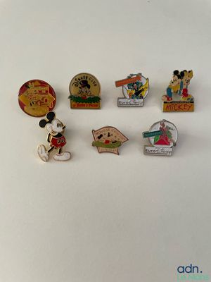several disney pin badges are arranged on a white surface