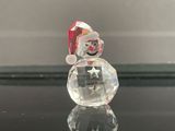 une figurine en verre représentant un bonhomme de neige assis sur une table