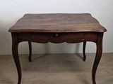 une vieille table en bois avec un tiroir en dessous, posée sur un parquet en bois massif