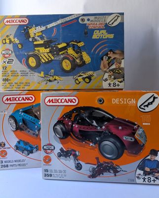 trois boîtes de legos de couleurs et de motifs différents sur une surface blanche