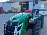 un tracteur vert garé devant un bâtiment, sur un parking