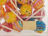 many lollipops in a clear box with a sign