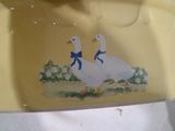 peinture représentant deux canards sur une assiette jaune ornée d'un nœud bleu