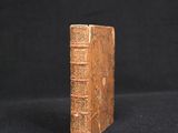 an old book sitting on top of a black cloth covered table