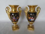two gold vases with pictures on them sitting on a table