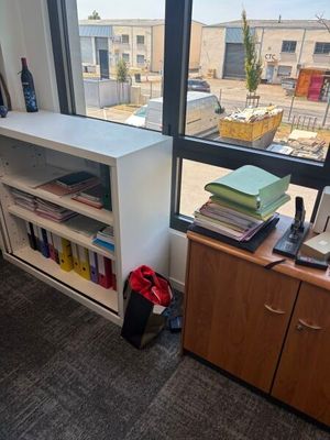 un bureau avec une bibliothèque et une chaise devant une fenêtre