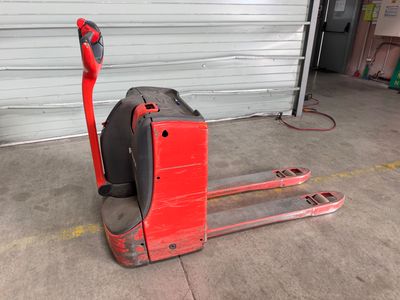 un chariot élévateur rouge garé devant la porte d'un garage