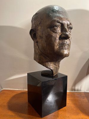a bust of a man sitting on a table next to a lamp